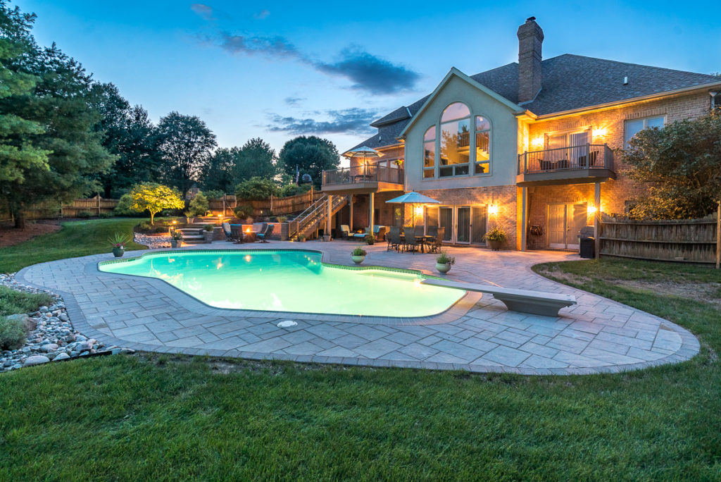 An image of an illuminated home with a pool in the foreground.