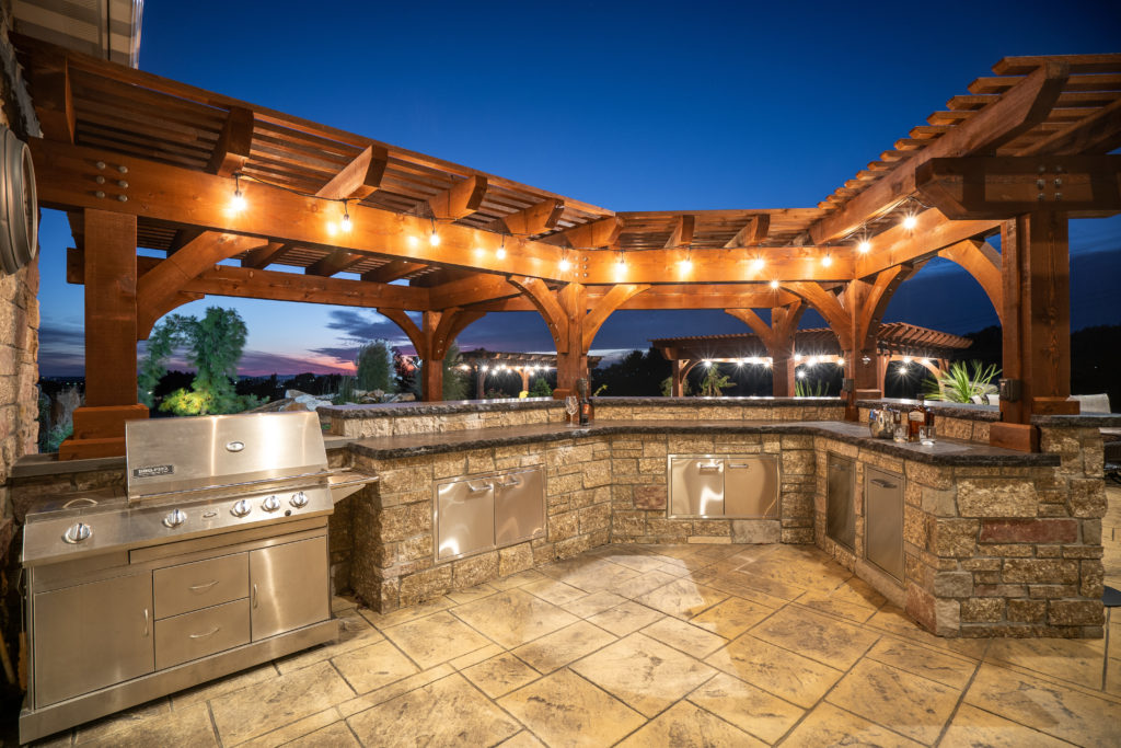 An image of an outdoor kitchen with a wooden overhead structure.